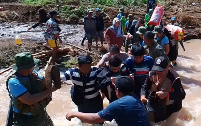 <p>ISOLATED. Officials of the Bangsamoro Autonomous Region in Muslim Mindanao brave the strong river current to bring aid Sunday (October 30, 2022) to Barangay Matuber, Datu Blah Sinsuat, Maguindanao del Norte. Barangay Matuber has been isolated due to a damaged bridge and road network following the onslaught of Severe Tropical Storm Paeng. <em>(BARMM photo)</em></p>
