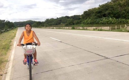 <p><strong>LAOAG BYPASS ROAD</strong>. A young biker cycles along the Laoag bypass road in Ilocos Norte in this undated photo. The city government will soon light up the highway with solar-powered street lights to reduce traffic accidents in the area. <em>(Photo by Leilanie Adriano)</em></p>