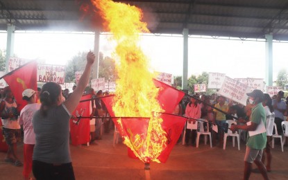 <p><strong>REJECTED</strong>. Residents of remote villages in Calatrava town, Negros Occidental province burn the replica flags of the Communist Party of the Philippines-New People’s Army during a peace rally held at Barangay Marcelo covered court on Monday (Nov. 7, 2022). About 400 individuals displayed placards condemning the NPA atrocities and took their oath of allegiance to the government while former NPA Yunit Militia members surrendered five firearms.<em> (Photo courtesy of 79th Infantry Battalion, Philippine Army)</em></p>
