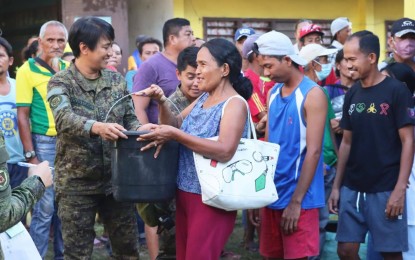 <p><strong>RELIEF OPERATION.</strong> A soldier of the Army's 10th Infantry Division hands over a pail of hygiene kit to a typhoon victim in Maguindanao during a relief operation on Nov. 13, 2022. The 10ID raised PHP697,000 from their subsistence allowance to help in the relief operations for the calamity victims.<em> (Photo courtesy of 10ID)</em></p>