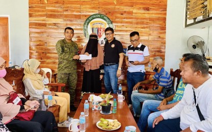 <p><strong>FINANCIAL ASSISTANCE.</strong> Brig. Gen. Domingo Gobway, Joint Task Force (JTF)-Basilan commander (left, standing) led the distribution of the government’s financial assistance on Wednesday (Nov. 16, 2022) to the families of the seven Moro Islamic Liberation Front (MILF) members slain in skirmishes with military forces last week in Barangay Ulitan, Ungkaya Pukan, Basilan. Assisting Gobway distribute the aid is Dan Asnawie (2nd from right, standing), a member of the BARMM parliament and commander of the MILF's 114th Base Command in the province.<em> (Photo courtesy of JTF-Basilan)</em></p>