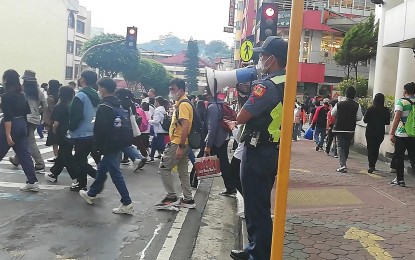 <p><strong>SAFETY MARSHAL</strong>. A police officer uses a public address system in this undated photo in October 2022 to remind the public crossing one of the busy pedestrian lanes on Session Road about ordinances implemented like the prohibition to use gadgets while walking. City tourism officer Aloysius Mapalo said Monday (Nov. 21, 2022) safety marshals will be seen in parks, tourist destinations and establishments to remind the public about their safety and the city’s ordinances.<em> (PNA file photo by Liza T. Agoot)</em></p>