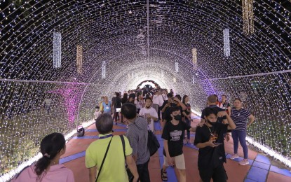 <p>People walking under the so-called light tunnel at the Quezon Memorial Circle <em>(PNA photo by Joey Razon)</em></p>