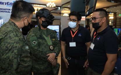 <p><strong>LATEST TRENDS.</strong> Acting Army chief-of-staff and concurrent Army Inspector General Maj. Gen. Jose Eriel Niembra (2nd from left) fits out a helmet-mounted night vision gear during the information and communications technology (ICT) exhibit at the Philippine Army Officers' Clubhouse in Fort Bonifacio Tuesday (Nov. 22, 2022). The exhibit is part of the Philippine Army's two-day Signal Family Conference. <em>(Photo courtesy of Philippine Army)</em></p>