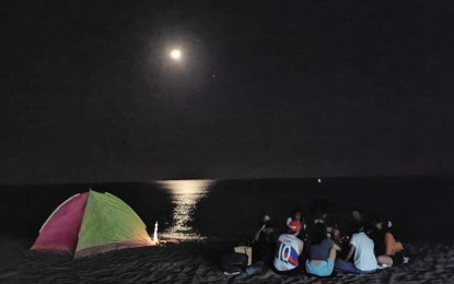 <p><strong>NIGHT CAMPING IN CALAYAB</strong>. Beachgoers enjoy camping under the moonlight at the Calayab beach in Laoag City in this undated photo. Calayab village chief Marvelyn Padayao said Thursday (Dec. 1, 2022) there has been a steady rise of visitors to the beach, particularly during weekends and holidays, due to its budget-friendly amenities. <em>(PNA photo by Leilanie Adriano) </em></p>