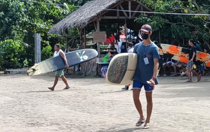 <p><strong>SURFING</strong>. Surfers carry their surfboards during the competition in Borongan City, Eastern Samar in this undated photo. Days before the end of the 3rd leg of the Philippine National Surfing Championship, the city government here on Thursday (Dec. 1, 2022) announced the schedule of their hosting next year.<em> (PNA photo by Roel Amazona)</em></p>