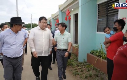 <p><strong>HOUSING PROJECT.</strong> President Ferdinand R. Marcos Jr. and National Housing Authority (NHA) general manager Joeben Tai inspect houses turned over by the NHA to 30,000 Filipino families in Naic, Cavite on Monday (Dec. 5, 2022). He said putting up more high-rise houses may help address the country’s housing backlog of more than 6.5 million. <em>(Screengrab from RTVM)</em></p>