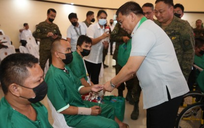 <p><strong>GIFT GIVING. </strong>Department of National Defense officer in charge, Undersecretary Jose C. Faustino Jr. (right), shares a light moment with combat-wounded troops during the gift-giving and visitation activity at the function hall of the Army General Hospital in Fort Bonifacio, Metro Manila on Dec. 6, 2022. Faustino said the gift-giving activity is meant to uplift the morale of combat-wounded soldiers and recognize their sacrifice and service to the country. <em>(Photo courtesy of PA) </em></p>