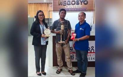 <p><strong>INNOVATIVE CRAFT.</strong> Jeeff De Asis (center), a coco craft maker holds his "hantic" or red ant coconut lampshade that won the Most Innovative Product during the Department of Trade and Industry (DTI) Antique's Panublion Heritage Fair in Iloilo City on Nov.20, 2022. Also in the photo are Acting Provincial Director Lynna Joy Cardinal and Trade and Industry Development Specialist Wilson Alian.  <em>(PNA photo courtesy of DTI Antique)</em></p>