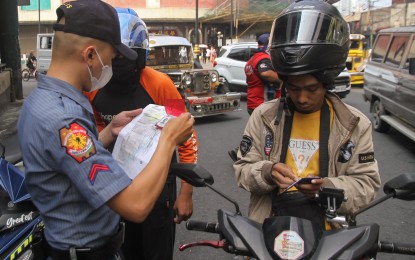 <p><strong>LICENSE CHECK.</strong> A motorcycle rider gets his driver's license checked by a police officer along Claro M. Recto Avenue in Manila on Dec. 12, 2022. The Land Transportation Office will launch soon a digital driver's license that will serve as alternative to the physical card.<em> (PNA photo by Yancy Lim)</em></p>