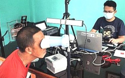 <p><strong>DELAYS IN RELEASE</strong>. An employee of the Philippine Statistics Authority in the Cordillera Administrative Region (PSA-CAR) get the iris scan of individuals registering for the national identification (ID) in 2021. PSA-CAR regional director Villafe Alibuyo on Wednesday (Dec. 14, 2022) called on the public to be patient amid delays in the release of national ID cards. She assured them that agencies involved in the Philippine Identification System program are doing their best to release copies of the IDs. <em>(PNA file photo by Liza T. Agoot)</em></p>