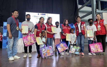 <p><strong>SERVICE CARAVAN FOR IPs</strong>. Department of Social Welfare and Development (DSWD) Assistant Secretary Irene Dumlao (3rd from left) and DSWD-7 regional director Shalaine Marie Lucero pose with government officials and indigenous peoples children during the service caravan at Hoops Dome, Lapu-Lapu City, Cebu on Wednesday (Dec. 21, 2022). About a hundred Ati and Badjao children received certificates issued by the Philippine Statistics Authority as proof of their birth. <em>(Photo courtesy of DSWD-7)</em></p>