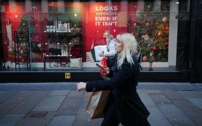 <p>People walk past a promotional sign in Manchester, Britain, Dec. 13, 2022. <em>(Photo by Jon Super/Xinhua)</em></p>