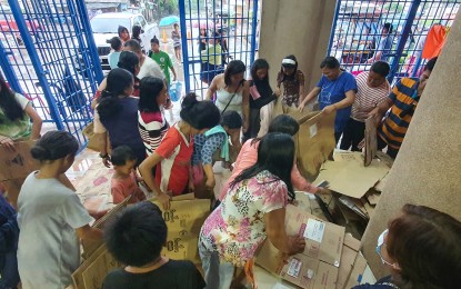 <p><strong>TEMPORARY REFUGE</strong>. Evacuees get carton sheets to make up for their temporary bedding at the Arturo S. Lugod Gymnasium in Gingoog City, Misamis Oriental province on Monday (Dec. 26, 2022), after their houses were affected by flooding caused by "shear line" rains. The province of Misamis Occidental reported six casualties from landslides and drowning. <em>(PNA photo by Nef Luczon)</em></p>