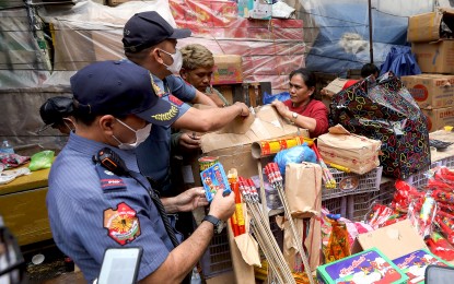 <p><strong>CRACKDOWN.</strong> Two police officers from the Manila Police District (MPD) Station 11, inspect and confiscate illegal firecrackers at some firecracker stalls along Tabora Street in Divisoria, Manila on Dec. 27, 2022. Union of Local Authorities of the Philippines president and Quirino Governor Dax Cua on Thursday (Dec. 28) urged his fellow local leaders to continue implementing Executive Order 28 banning firecrackers to protect their constituents from undue harm that these may cause. <em>(PNA file photo)</em></p>