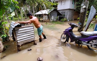 <p><strong>FLOODWATERS.</strong> A resident of Barangay Guadalupe, Carmen, Davao del Norte, fixes an improvised cage on Thursday (Jan. 5, 2023) amid the floodwaters. Massive flooding hit the province on Wednesday due to the effects of a low pressure area. <em>(PNA photo by Robinson Niñal Jr.)</em></p>