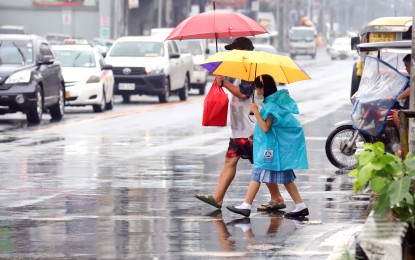 <p>A school girl protects herself from the rain using umbrella and raincoat. <em>(PNA photo by Robert Oswald Alfiler)</em></p>