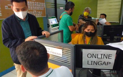 <p><strong>ONLINE SERVICES.</strong> John Patrick Celis (wearing black jacket) head of the Lingap Para sa Mahirap Assistance Program, assists a client who avails of online services on Friday (Jan.6, 2023) at one of their centers at the Southern Philippines Medical Center in Davao City. Celis says the center has  catered at least to 7,835 online clients in 2022.<em> (PNA photo by Robinson Niñal Jr.)</em></p>