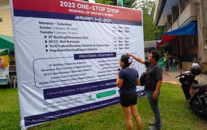 <p><strong>REGISTRATION FLOW.</strong> Two Dabawenyos check the business permit registration flow on Tuesday (Jan. 10, 2023) on a giant tarpaulin installed outside the Toril District Hall in Davao City. The one-stop shop is a streamlined processing service that aims to save taxpayers’ time and money by simplifying the business permit application process. <em>(PNA photo by Robinson Niñal Jr.)</em></p>
