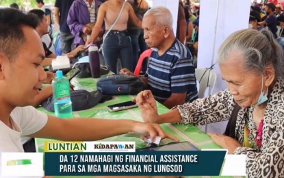 <p><strong>AID TO FARMERS.</strong> A female farmer-beneficiary receives the PHP5,000 cash during the distribution of the PHP3.5 million financial aid by the Department of Agriculture–Soccsksargen in Kidapawan City, North Cotabato, on Thursday (Jan. 12, 2023). At least 100 city farmers benefited from the program.<em> (Photo courtesy of Kidapawan CIO)</em></p>