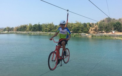 <p><strong>NATURE PARK</strong>. A local tourist tries the bike zipline offered at the Umok ni Siwawer Eco-Park in Vintar town, Ilocos Norte province in this undated photo. This year, the local government unit of Vintar plans to establish more amenities including a food park to entice more visitors. <em>(File photo by Leilanie Adriano)</em></p>