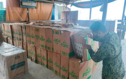 <p><strong>CONTRABAND.</strong> A cop inspects the boxes containing PHP5.5 million worth of smuggled cigarettes that were confiscated from five suspects on a motorboat in Barangay Tigtabon, Zamboanga City on Saturday (Jan. 21, 2023). The shipment reportedly came from the town of Jolo in Sulu province.<em> (Courtesy of 2ZCMFC)</em></p>