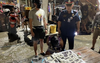 <p><strong>ANTI-DRUG STING.</strong> Drug suspect Vincen Rodriguez, 21, an e-bike driver, kneels in front of around one kilo of suspected shabu worth PHP7.1 million, confiscated from him during a sting operation in the coastal barangay of Pasil in Cebu City on Monday night (Jan. 23, 2023). Cebu City Police Station 6 chief, Major Francis Renz Talosig (standing right, in uniform), said on Tuesday (Jan. 24) that Rodriguez is listed as a regional-level drug personality, according to the police drug database. <em>(Photo contributed by Romeo Marantal) </em></p>