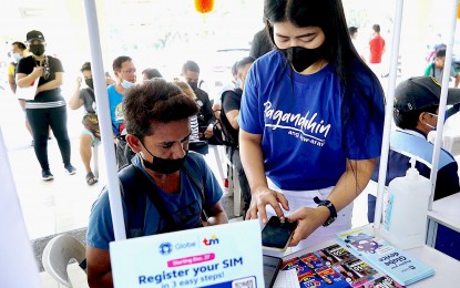 <p><strong>ASSISTED REGISTRATION.</strong> A Globe Telecom Inc. (Globe) staff member helps register a subscriber identity module (SIM) card at a stall at the Quezon City Hall on Jan. 24, 2023. The National Telecommunications Commission and the Philippine Statistics Authority are set to hold joint caravans that would allow the public to register their SIM cards and secure their National ID at the same site.<em> (PNA photo by Ben Briones)</em></p>