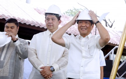 <p><strong>HOUSING PROGRAM.</strong> President Ferdinand R. Marcos Jr. (right) puts on his safety hat to start off the groundbreaking ceremony of the Pambansang Pabahay Para sa Pilipino housing project - Batasan Development Urban Renewal Plan in Batasan Hills, Quezon City on Tuesday (Jan. 31, 2023). Right on the first day of his administration, Marcos instructed that affordable housing units be available to homeless Filipinos. <em>(PNA photo by Alfred Frias)</em></p>