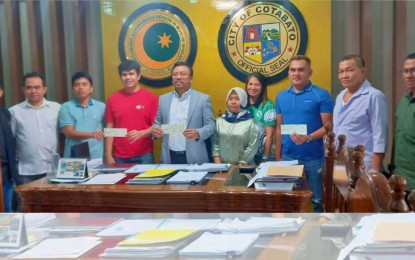 <p><strong>BARANGAY HALLS.</strong> Cotabato City Mayor Bruce Matabalao (5th from left) and village officials show their PHP3.5 million worth of checks each to fund nine new barangay halls in the city by the BARMM regional government. The modern village halls set for construction have a budget of PHP31.5 million.<em> (Photo courtesy of MILG-BARMM)</em></p>