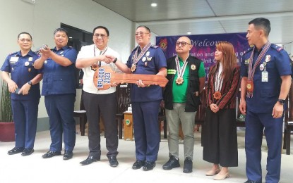 <p><strong>TURNOVER</strong>. Department of Public Works and Highways (DPWH) -Cordillera Regional Director Engr. Khadaffy Tanggol (3rd from left) turns over to Philippine National Police chief Gen. Rodolfo Azurin (4th from left) a symbolic key to a newly constructed building. Azurin urged the DPWH to call the police to secure road construction projects in critical areas to ensure that the administration’s goal of pursuing development in the country will not be stalled. <em>(PNA photo by Liza T. Agoot)</em></p>