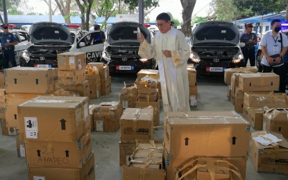 <p><strong>CAPABILITY BOOST</strong>. Rev. Fr. Marcel Gonzales blesses the 25 patrol cars and 670 units of radio communication equipment provided by the Cavite provincial government to the police on Tuesday (Feb. 21, 2023). The donation served as the provincial government’s show of all-out support to the Philippine National Police modernization program.<em> (PNA photo by Rossel Calderon)</em></p>