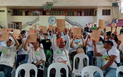 <p><strong>NEW LANDOWNERS.</strong> Several farmers of the 184 agrarian reform beneficiaries (ARBs) raise their certificates of land ownership awards after the Department of Agrarian Reform awarded them on Feb. 25, 2023 the unused government lands in Carmen town, North Cotabato province. At least 195.9 hectares of land were distributed to the ARBs. <em>(Photos courtesy of DAR-North Cotabato)</em></p>