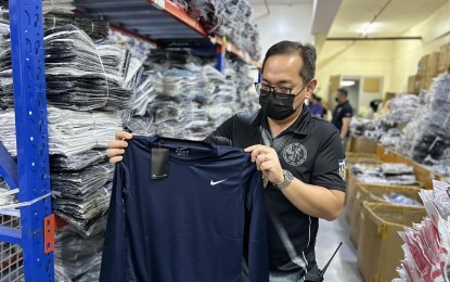 <p><strong>FAKE GOODS. </strong>Intelligence Officer 3 Alvin Enciso, chief of the Customs Intelligence and Investigation Service at the Manila International Container Port (CIIS-MICP), inspects counterfeit bags and apparel from a storage facility raided by authorities in Binondo, Manila on Tuesday (Feb. 28, 2023). These counterfeit items have infringed trademarks, such as Nike, Coach, Adidas, Guess, Louis Vuitton, Dior, and Gucci, among others. <em>(Photo courtesy of BOC)</em></p>