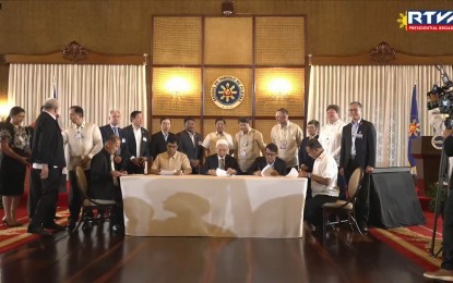 <p><strong>CEREMONIAL SIGNING</strong>. President Ferdinand R. Marcos Jr. witnesses the ceremonial signing of the memorandum of agreement (MOA) between the government and private sector on the implementation of Kapatid Angat Lahat for Agriculture Program (KALAP) at the Ceremonial Hall of Malacañang Palace on Monday (March 6, 2023). The MOA aims to promote inclusive economic growth using Go Negosyo’s framework of providing farmers and micro, small and medium enterprises (MSMEs) access to money, markets and mentoring. <em>(Screengrab from RTVM)</em></p>