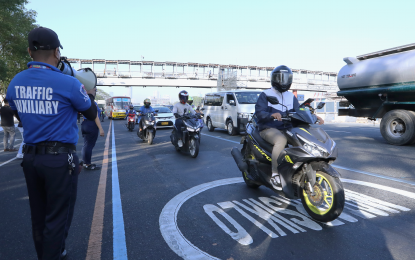 <p><strong>DRY RUN.</strong> A Metropolitan Manila Development Authority traffic auxiliary personnel uses a megaphone to remind motorists and motorcycle riders along Commonwealth Avenue in Quezon City on March 8, 2023 about the implementation of the dry run of the exclusive motorcycle lane from March 9 until March 19. The implementation of the motorcycle lane aims to reduce the number of fatal road crashes involving motorcycles and to improve traffic flow.<em> (PNA photo by Joey O. Razon)</em></p>