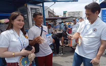 <p><strong>DIGITAL PAYMENT</strong>. Bacolod City Mayor Alfredo Abelardo Benitez (right) scans the QR code of a pandesal (bread) vendor at Libertad Market to pay for his purchase, during the launching of the Palengke-QR Ph Plus cashless payment system with Bangko Sentral ng Pilipinas (BSP) Deputy Governor Bernadette Romulo-Puyat (left) on Tuesday (March 14, 2023). Bacolod City is the first local government unit in Western Visayas region and the seventh in the country to launch the program with the BSP and the Department of the Interior and Local Government. <em>(PNA photo by Nanette L. Guadalquiver)</em></p>