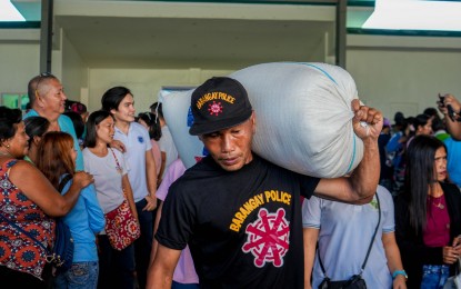 <p><strong>RICE ASSISTANCE.</strong> Undated photo shows a barangay tanod carrying a sack of rice which he received as assistance from the Sorsogon's provincial government. A total of 11,917 barangay workers from the entire province received a sack of rice each.<em> (Photo courtesy of Sorsogon PIO)</em></p>