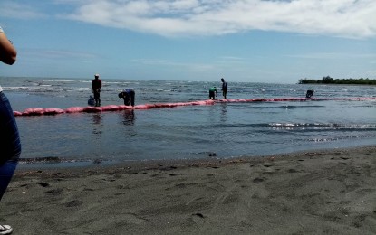 <p><strong>OIL SLICK</strong>. Disaster responders along with volunteer residents, put in place improvised spill booms after traces of oil slick were found in the waters and shoreline of Barangay Navotas, Calapan City on Friday (March 17, 2023). Residents are now banned from fishing and eating seafood from the area. <em>(Contributed photo)</em></p>