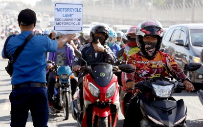<p><strong>THUMBS UP.</strong> A motorcycle rider flashes the thumbs-up sign to a traffic constable carrying a placard that reads "Motorcycle Lane Exclusive for Motorcycle," along Commonwealth Avenue in Quezon City on Friday (March 17, 2023). The dry run has been extended for another week to give way to road patching works and for motorists to get familiar with the new policy. <em>(PNA photo by Joey O. Razon)</em></p>