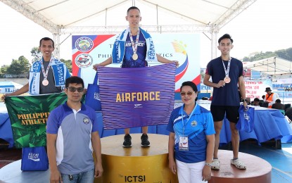 <p><strong>10K WINNER.</strong> Gold medalist Sonny Wagbos (center) holds the Philippine Air Force flag during the awarding ceremony of the men's 10,000m event of the ICTSI Philippine Athletics Championships at the Ilagan City Sports Complex on March 24, 2023. Also in photo are silver medalist Richard Salaño of Philippine Army (left) and bronze medalist Eduard Josh Buenavista of the University of the Philippines. <em>(Photo courtesy of Philippine Athletics Track and Field Association)</em></p>