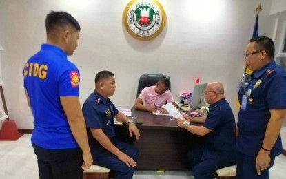 <p><strong>TOP COP ARRESTED.</strong> Members of the Criminal Investigation and Detection Group in Bangsamoro Autonomous Region in Muslim Mindanao (CIDG-BARMM) serve the arrest warrants against BARMM police director Brig. Gen. John Guyguyon (seated) inside his office in Camp SK Pendatun, Parang, Maguindanao, on Wednesday night (March 30, 2023). Guyguyon is facing two counts of syndicated estafa with the warrants issued by separate Quezon City regional trial courts.<em> (Photo courtesy of CIDG-BARMM)</em></p>
