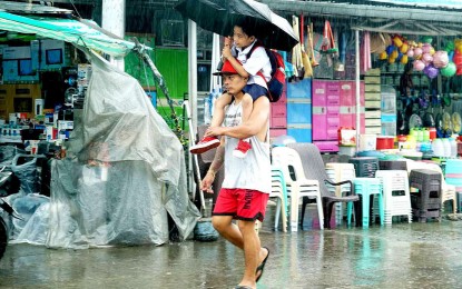 <p><strong>RAINY DAY.</strong> A man carries a boy over his shoulders as they share an umbrella on a rainy day in this undated photo. Most areas in the country will experience rain showers due to the southwest monsoon or<em> habagat</em> on Tuesday (Aug. 22, 2023), the weather bureau said.<em> (PNA file photo)</em></p>