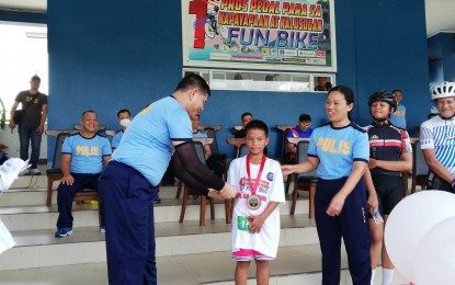 <p><strong>WINNER</strong>. Police Regional Office 5 (Bicol) Deputy Director for Administration, Brig. Gen Limuel Obon (left), and Col. Lianne Van de Velde, Regional Community Affairs Development Division chief (right), hand over a cash prize and certificate to nine-year-old Angelo Jay Erebete, the youngest participant of the first “Pedal para sa Kapayapaan at Kalusugan” held at Camp Gen. Simeon Ola, Legazpi City on Saturday (April 15, 2023). The fun bike event kicked off at Camp Gen. Ola and proceeded to Daraga town, a 25-km. ride. <em>(PNA photo by Connie Calipay)</em></p>