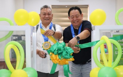 <p><strong>SERVICE DESK</strong>. Undated photo shows PhilHealth-Bicol Vice President Henry Almanon (left) and Libon town Mayor Wilfredo Maronilla cutting the ribbon during the opening of the PhilHealth satellite service desk in the town. The desk caters to transactions such as registration, updating and printing of member data records and PhilHealth identification cards. <em>(Photo courtesy of PhilHealth-Bicol)</em></p>
