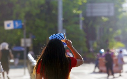 <p><strong>CAN'T STAND THE HEAT.</strong> A fan provides temporary shade for a pedestrian in Diliman, Quezon City on Thursday (May 4, 2023). Health experts advise ample covering from direct sunlight when going out, especially when temperature is at its peak between 10 a.m. and 4 p.m.<em> (PNA photo by Joan Bondoc)</em></p>