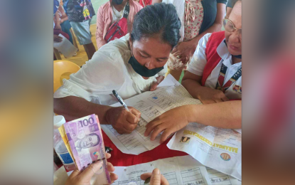 <p><strong>CASH FOR WORK.</strong> A female beneficiary of the cash-for work program in Magpet, North Cotabato signs a document for her cash-for-work payment during the Department of Social Welfare and Development-Soccsksargen KALAHI-CIDSS payout at the municipal gymnasium on Thursday (May 18, 2023). A total of 13,302 beneficiaries from three towns of the region received their pay.<em> (Photo courtesy of DSWD-12)</em></p>