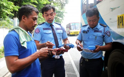<p><strong>ROAD SAFETY.</strong> Enforcers of the Land Transportation Office issue an obstruction and bald tire violation ticket to a public bus driver along East Avenue in Quezon City on May 22, 2023. In total, LTO National Capital Region Regional Director Roque Verzosa III said 1,737 apprehensions were made in May alone.<em> (PNA photo by Robert Oswald P. Alfiler)</em></p>