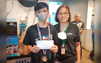 <p><strong>CHAMPION.</strong> GMG Youth Challenge Rapid Chess winner Christian Mendoza of Antipolo City (left) poses with branch manager Mimi Casas of the Open Kitchen Food Hall of Rockwell Business Center, Mandaluyong City during the awarding ceremony on Saturday (May 20, 2023). Mendoza scored 6.5 points to rule the tournament.<em> (Contributed photo)</em></p>