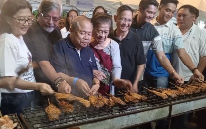 <p><strong>CHICKEN INASAL FESTIVAL</strong>. Officials of Bacolod City and guests check out chicken inasal cooked on a portion of the 320-meter-long grilling station set up along the main road of Megaworld’s The Upper East to culminate the three-day Chicken Inasal Festival on Sunday night (May 28, 2023). At least 3,000 sticks of various chicken parts were grilled during the event. <em>(PNA photo by Nanette L. Guadalquiver)</em></p>